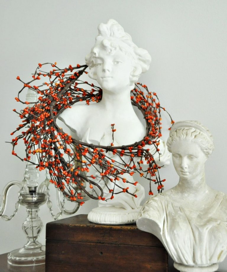 Bust with simple, fall, berry garland draped around her shoulders.